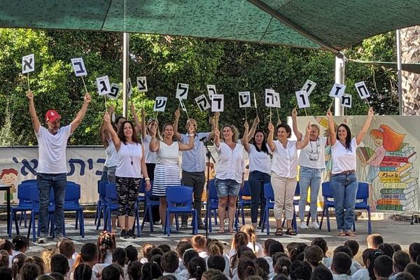 מורות מניפות שלטים עם אותיות