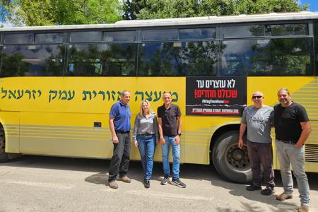 ראשת המועצה, שלומית שיחור וצוות מחלקת התחבורה ליד אוטובס עם מדבקה להחזרת החטופים