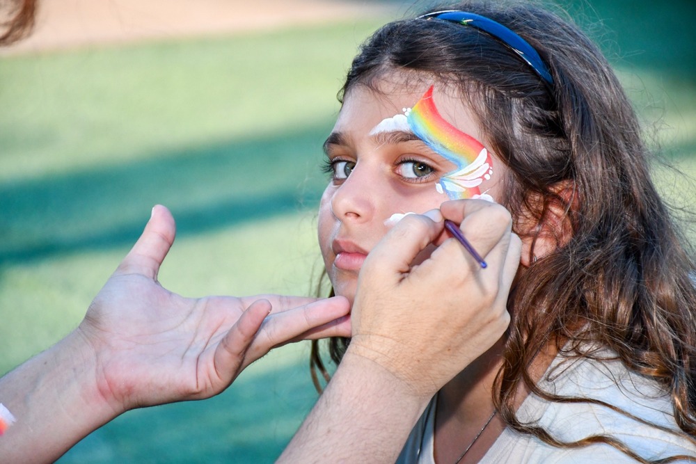 מאפרת מציירת לילדה ציור על הפנים